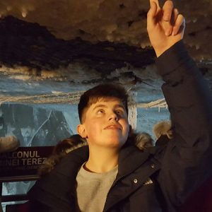 student touching the roof of a cave