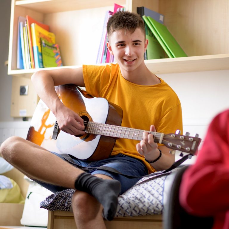 Boy playing the guitar in his dorm room